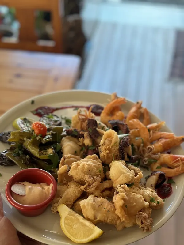 A plate of fried seafood mix: calamari, shrimps and octopus with lemon and a dip