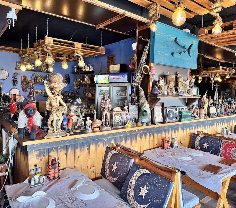 The long bar at Haxhi lined with figurines, under a timber ceiling and Edison bulbs