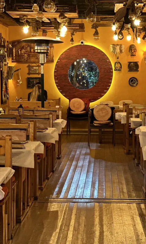 A timber-floored dining room leading to a glowing round porthole window