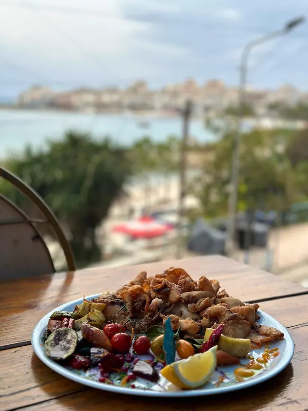 A seafood plate on a terrace table overlooking the beach and town of Sarandë
